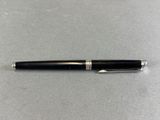 a pen sitting on top of a table next to a metal object