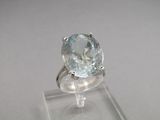 an oval aquamarinee stone set in a white gold ring on a clear acrylic stand