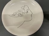 a white plate with a drawing of a woman ' s face on it