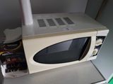 a microwave sitting on top of a counter next to a bottle of beer