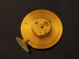 a gold clock that is sitting on a black surface