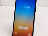 the back of a black phone with a blue screen on a white surface