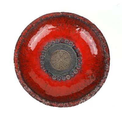 a red bowl with a black center on a white surface