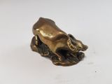 brass figurine of a bull on a rock on a white surface