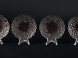 trois plats plaqués argent posés sur des supports, sur fond noir