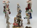 trois figurines représentant des personnes et un chien, posées sur une surface blanche