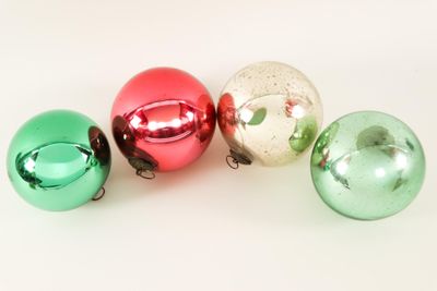 four shiny christmas ornaments are arranged in a row on a white surface