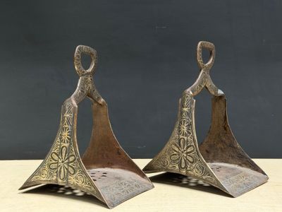 pair of antique brass bells on wooden stand with black background