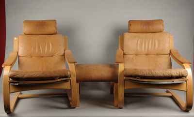 deux fauteuils inclinables en cuir marron et un repose-pieds dans une pièce avec un rideau rouge