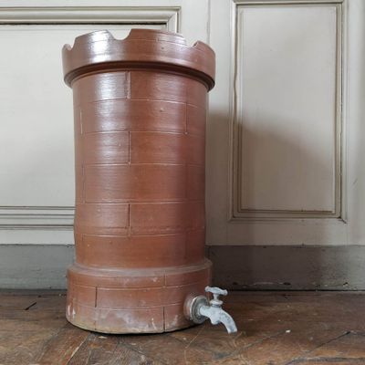 a large brown pot sitting on the floor next to a faucet