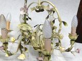 a chandelier with flowers and candles on it on a table