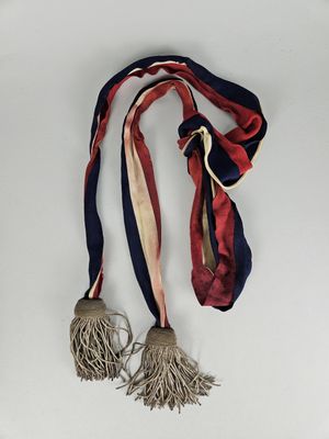 a red, white, and blue ribbon with tassels hanging from it