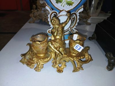 a gold figurine on a white table with a blue vase in the background