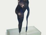 a sculpture of a woman standing on a glass platform