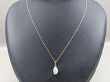 a gold necklace with a white pearl pendant on a mannequin