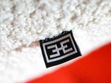 a close up of a red and white blanket with a black and white logo