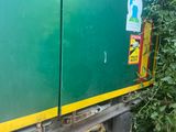 a green and yellow truck parked next to a bush