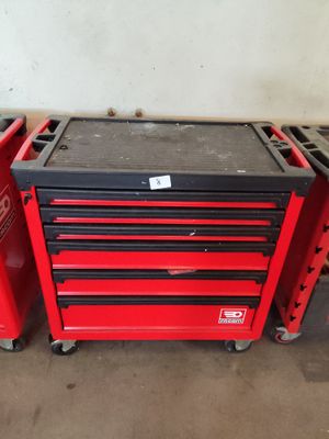 une boîte à outils rouge et une boîte à outils noire à roulettes dans un garage