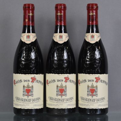 trois bouteilles de vin rouge sont posées sur une table en verre