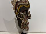 an image of a wooden mask on a stand on a white surface