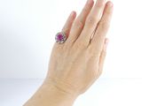 a woman ' s hand holding a ring with a purple stone
