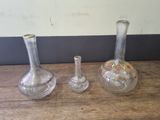 three glass vases sitting on a table next to each other