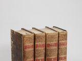 three old books sitting on top of each other on a white surface