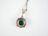 a silver necklace with a green stone in the center