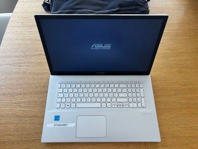 un ordinateur portable posé sur une table, avec un sac dessus