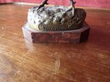 a statue of a bird sitting on a rock on a table