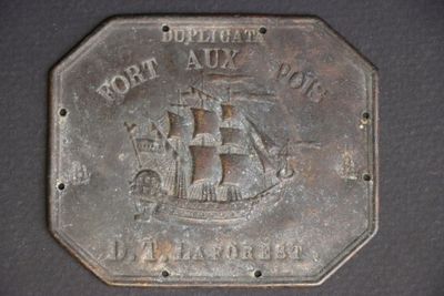 a close up of a metal plate with a ship on it
