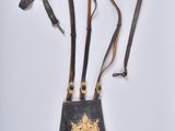 a black purse with a gold emblem on the front and a brown strap