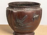 a brown vase with a bird on it sitting on a table