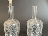 pair of etched glass decanters on a black background