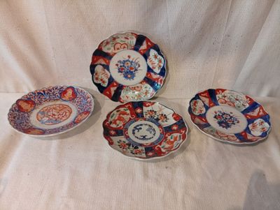 Plusieurs assiettes aux motifs variés sont disposées sur une nappe blanche