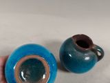 a person holding a small blue vase and a smaller blue vase