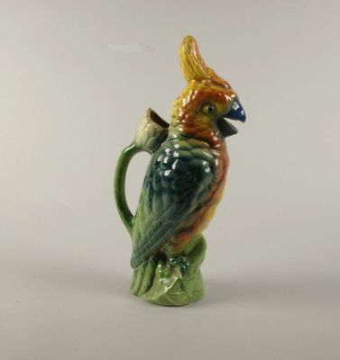 un perroquet en céramique posé sur une tasse verte