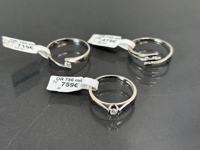 trois bagues en argent munies d'étiquettes, posées sur une table