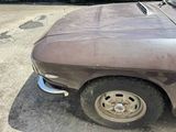 a rusted car parked in a parking lot next to a building