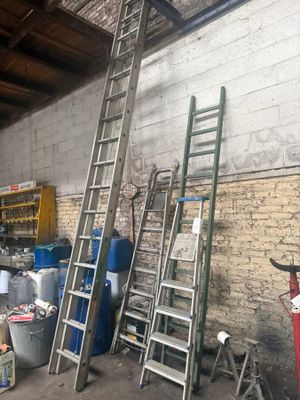 several ladders leaning against a brick wall in a garage