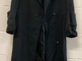 a black coat hanging on a wall next to a white brick wall