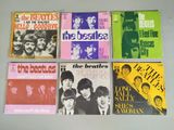 the beatles album covers are lined up on a table