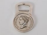 une image représentant un décapsuleur en forme de pièce de monnaie sur lequel figure le visage d'une femme