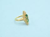 a close up of a gold ring with a green stone