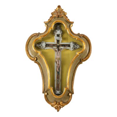 une croix accrochée au mur, encadrée d'un cadre doré