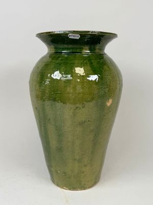un vase vert posé sur une surface blanche