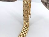 gold plated bracelet on a branch on a white background