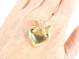 someone is holding a heart shaped ring with a cross on it
