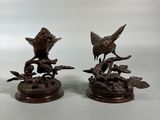 two bronze figurines of birds perched on a tree branch