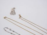 a group of three gold and silver necklaces on a white surface